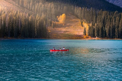 三人在红划艇蓝平静的水域在白天
